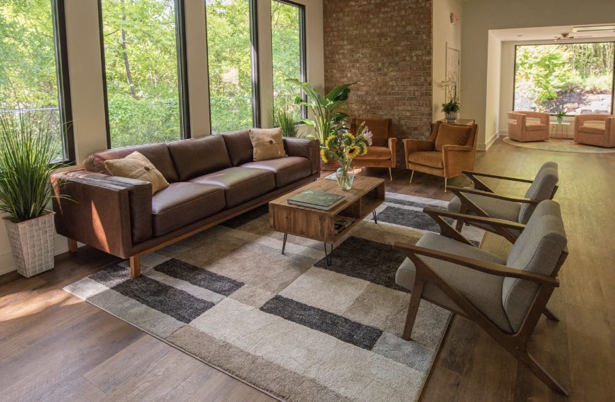 The Greenville office sitting room, with tall windows and a leather sofa